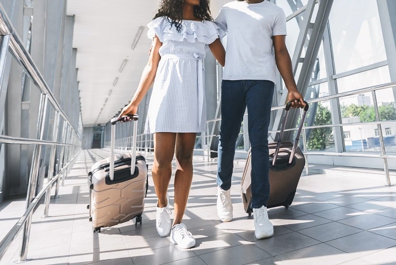 Couple at the airport. Image from https://www.messagemagazine.com/articles/spending-tips-that-will-save-you-as-you-plan-your-summer-travel/attachment/african-couple-walking-with-luggage-in-airport/