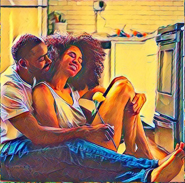 Black man and woman seated on floor, embracing